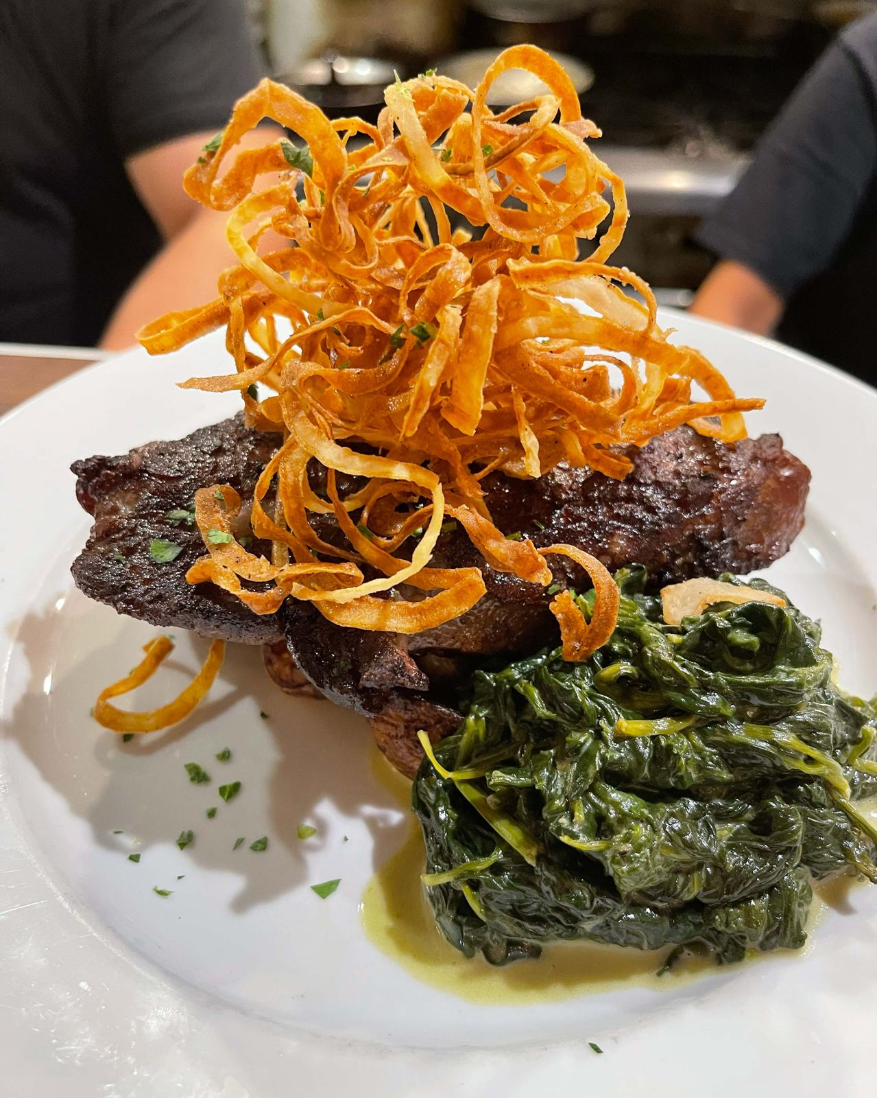 Steak with crispy onions and greens at Bistro Moulin